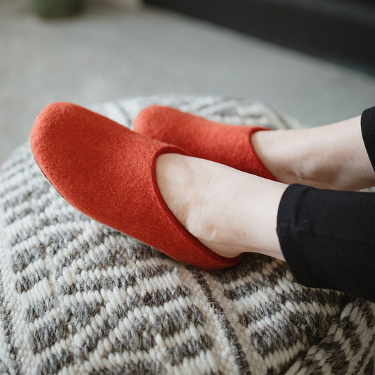 woman's feet wearing cozy wool felt slippers in spice red orange color