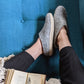 cozy grey wool slippers on a blue sofa with a blanket and a good book