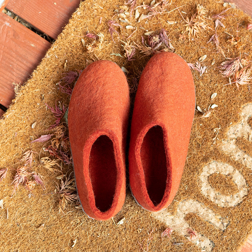 wool felt slippers on a doormat surrounded by leaves